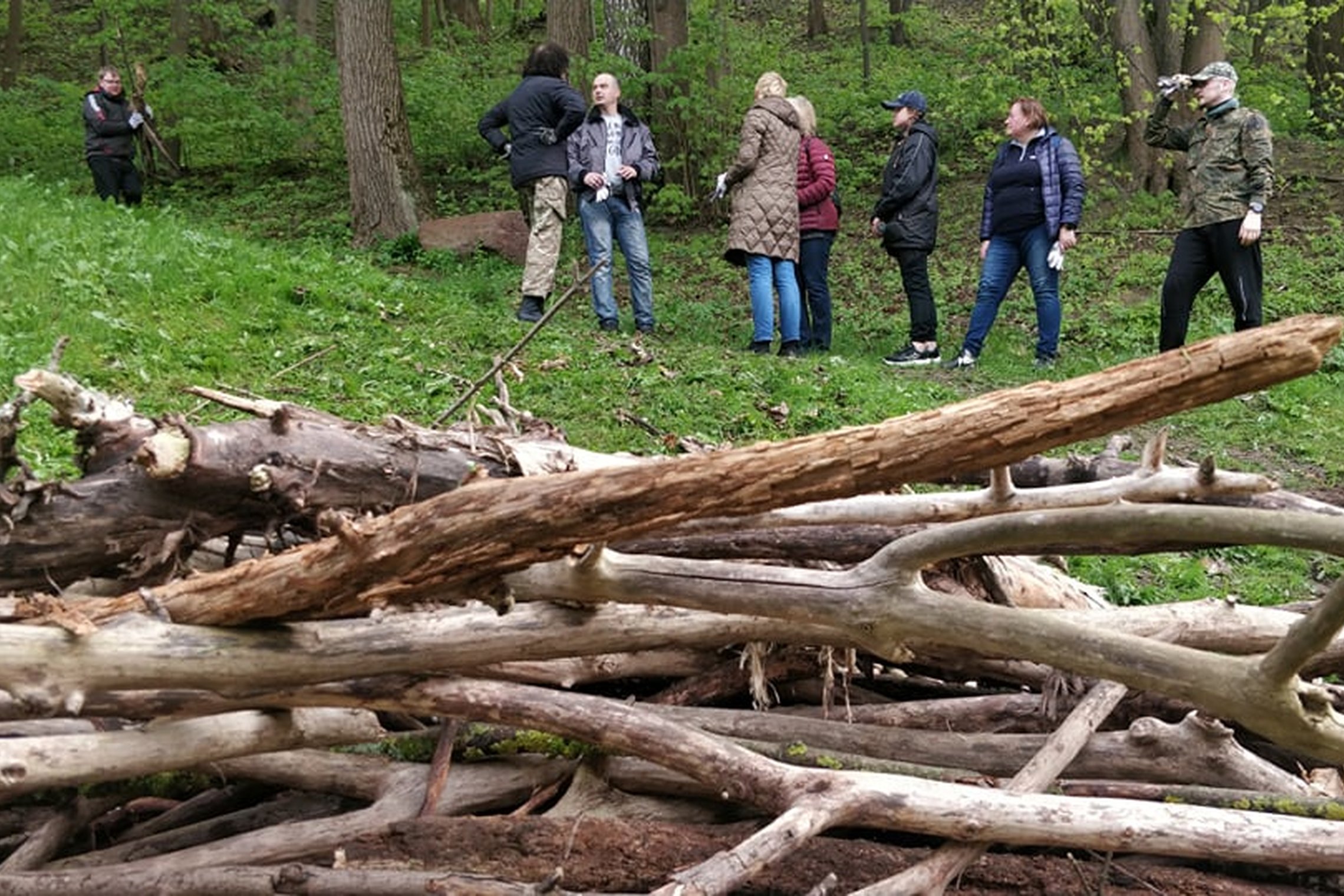 Vidaus reikalų ministerijos darbuotojai stovi ant tako. Nuotraukos apačioje šakų krūva.