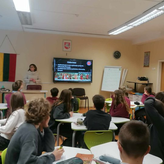 Mokiniai sėdi klasėje, edukatorė veda pamoką apie Buboninį marą.