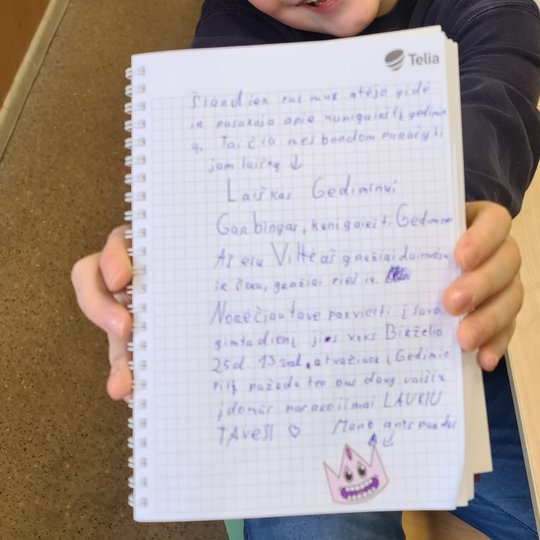 Mokinys rankose rodo sąsiuvinyje paprašytą laišką Gediminui.