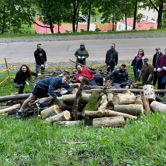 Padėjėjai pozuoja šalia supjautų medžių.
