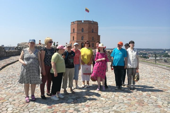 Ekskursijos dalyviai ant Gedimino kalno viršutinės terasos. Jiems už nugarų matosi Gedimino pilis.  