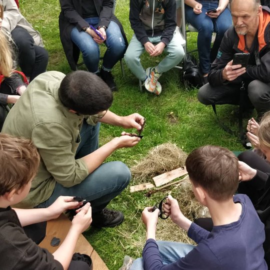 Archeologas Algirdas Kalinauskas šalia Vilniaus pilių kupolo žiebia ugnį naudodamas titnagą ir skeltuvą.