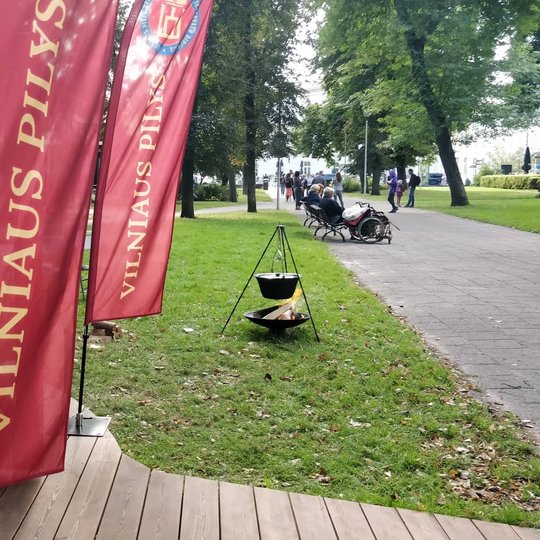 Vilniaus pilių kupoli įėjimas su vėliavomis. Dešinėje matosi laužas su katilu.