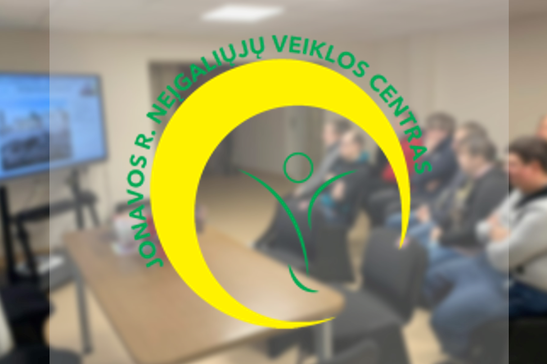Jonavos neįgaliųjų veiklos centro lankytojai kambaryje klausosi paskaitos nuotoliniu būdu. Nuotraukos priekyje Jonavos neįgaliųjų veiklos centro logotipas.