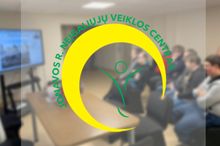 Jonavos neįgaliųjų veiklos centro lankytojai kambaryje klausosi paskaitos nuotoliniu būdu. Nuotraukos priekyje Jonavos neįgaliųjų veiklos centro logotipas.