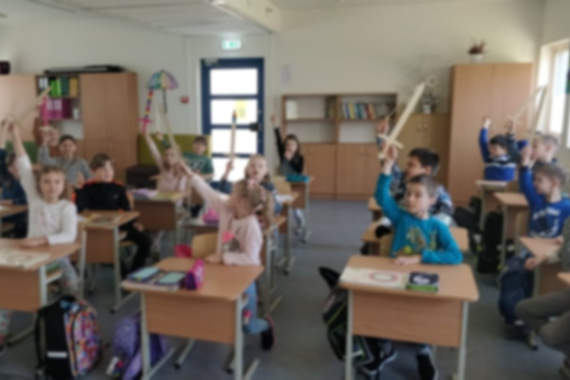 Antrokai klasėje, iškėlę medinius kalavijus į viršų.