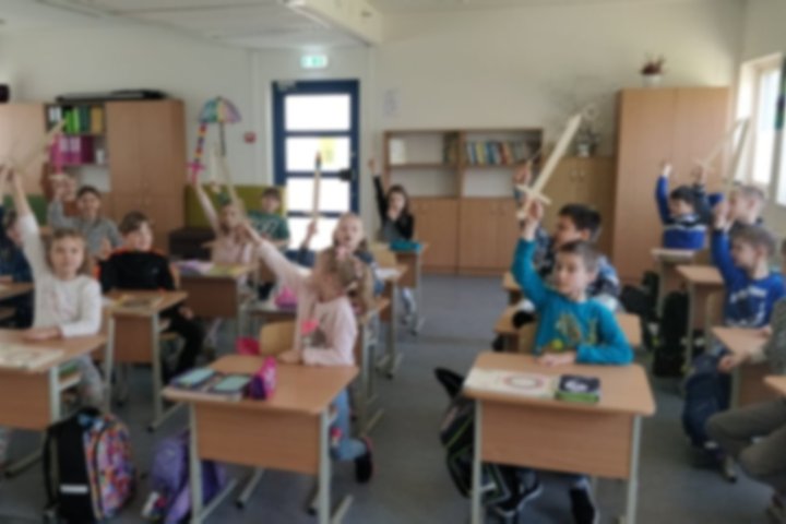 Antrokai klasėje, iškėlę medinius kalavijus į viršų.