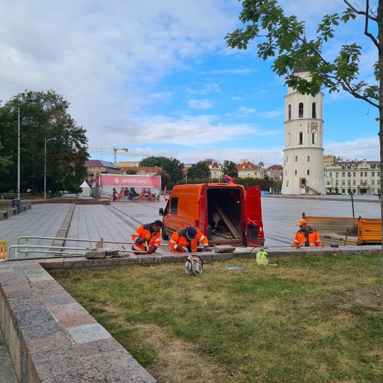 UAB „Grinda“ darbuotojai tvarko atraminę sienutę. Jiems už nugarų Katedros aikštė, matosi varpinės bokštas.