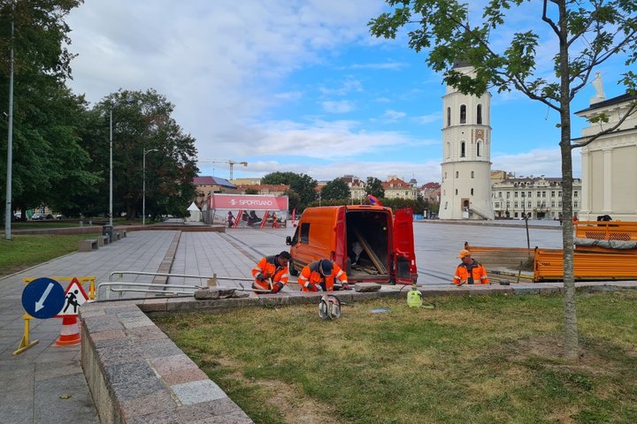 UAB „Grinda“ darbuotojai tvarko atraminę sienutę. Jiems už nugarų Katedros aikštė, matosi varpinės bokštas.