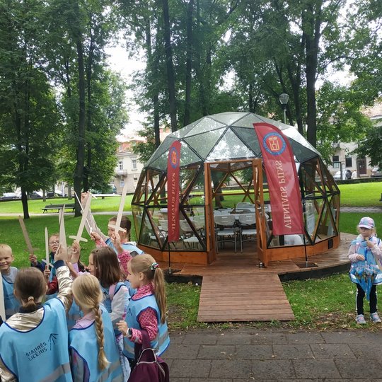 Šalia Vilniaus pilių kupolo vaikai iškėlę medinius kalavijus.