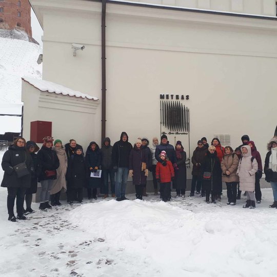 Grupė ekskursijos dalyvių prie Valdovų rūmų vartų.