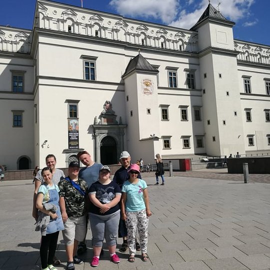 Ekskursijos dalyviai pozuoja nuotraukai. Jiems už nugarų Vadovų rūmų pietiniai vartai. 
