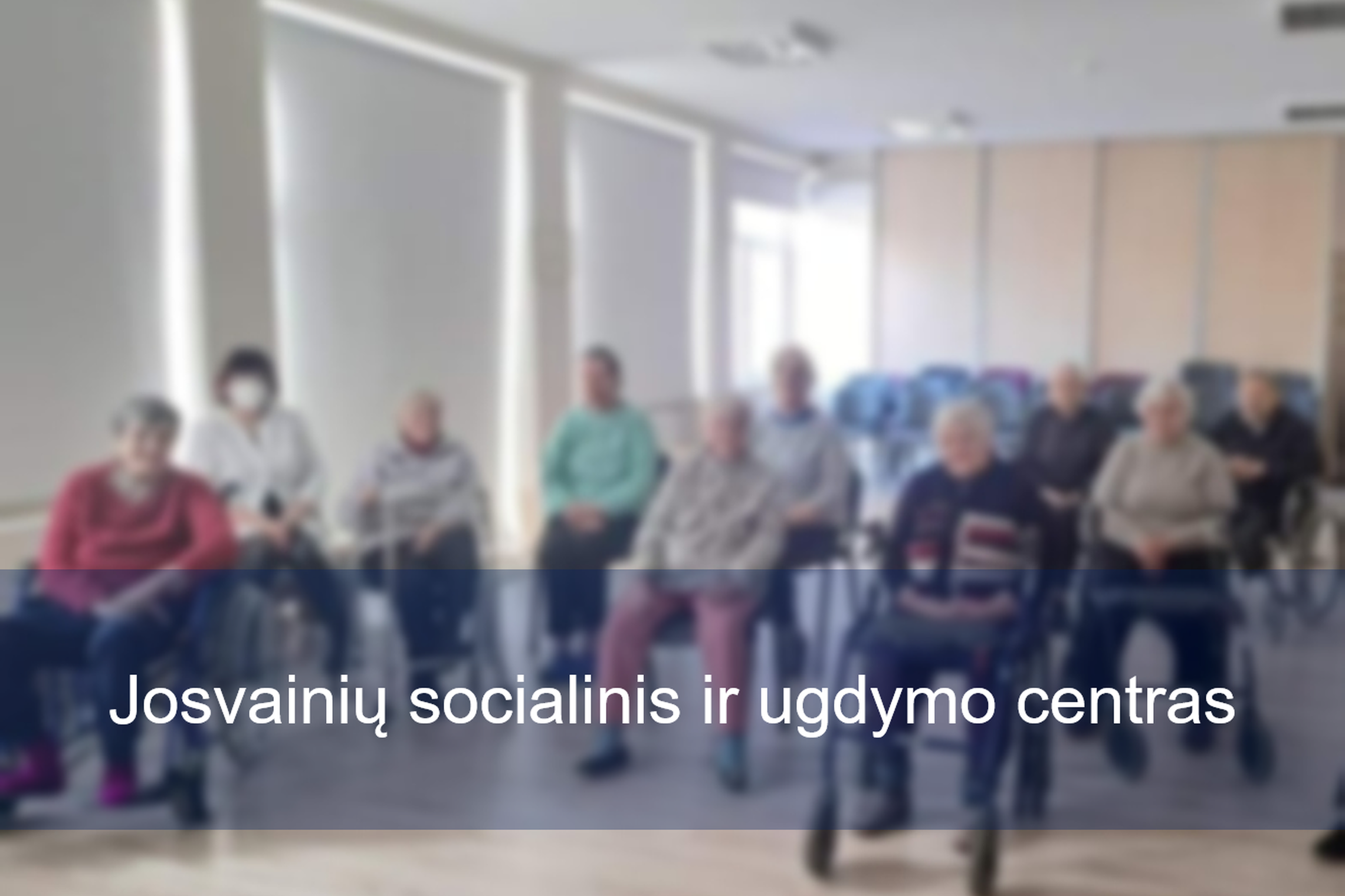 Josvainių socialinio ir ugdymo centro gyventojai klausosi paskaitos. Nuotraukos priekyje įstaigos pavadinimas.
