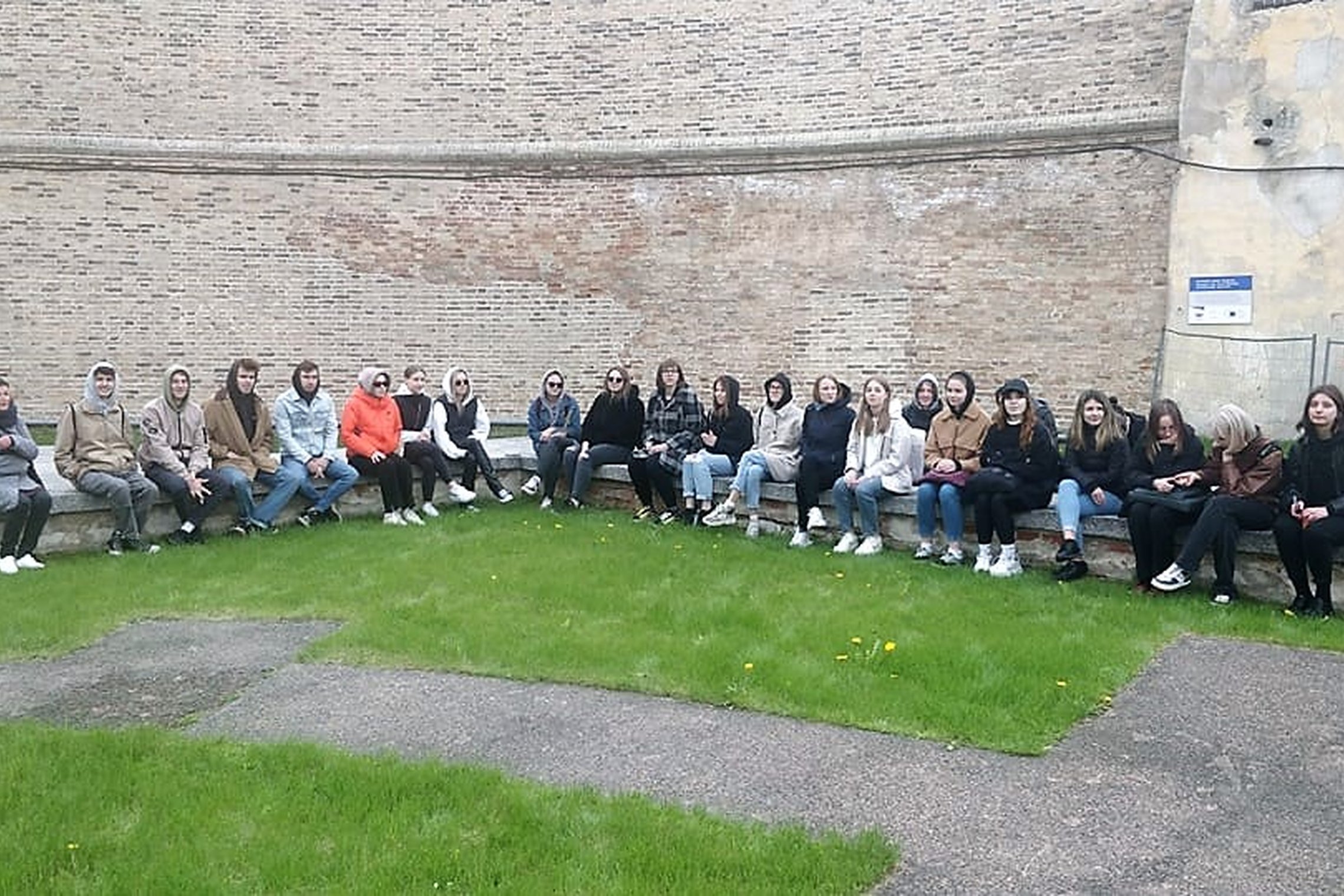Studentai sėdi ant Barboros bažnyčios pamatų, šalia didžiosios atraminės Gedimino kalno sienos. 
