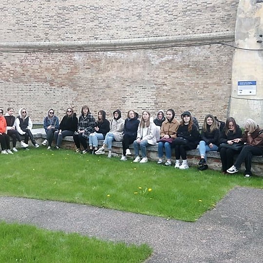 Studentai sėdi ant Barboros bažnyčios pamatų, šalia didžiosios atraminės Gedimino kalno sienos. 