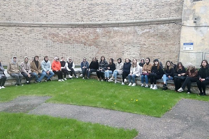 Studentai sėdi ant Barboros bažnyčios pamatų, šalia didžiosios atraminės Gedimino kalno sienos.