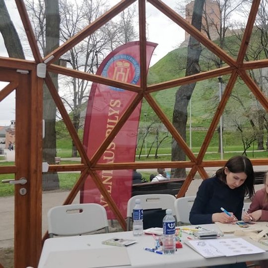 Mama su dukrele dekoruoja medžiaginį maišelį. Viskas vyksta Vilniaus pilių kupole.