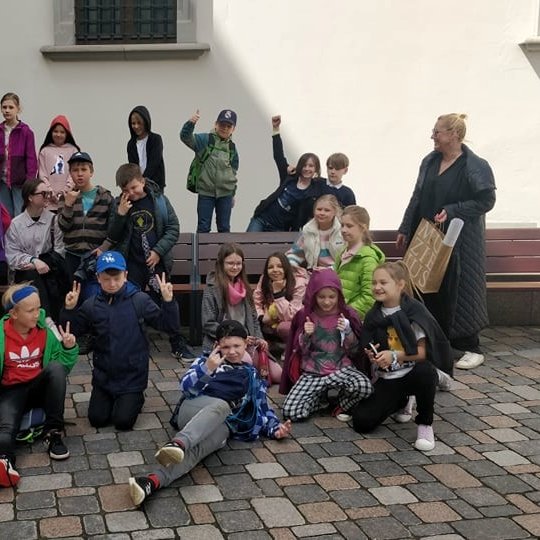 Trečiokai kartu su mokytoja pozuoja nuotraukai šalia Valdovų rūmų.