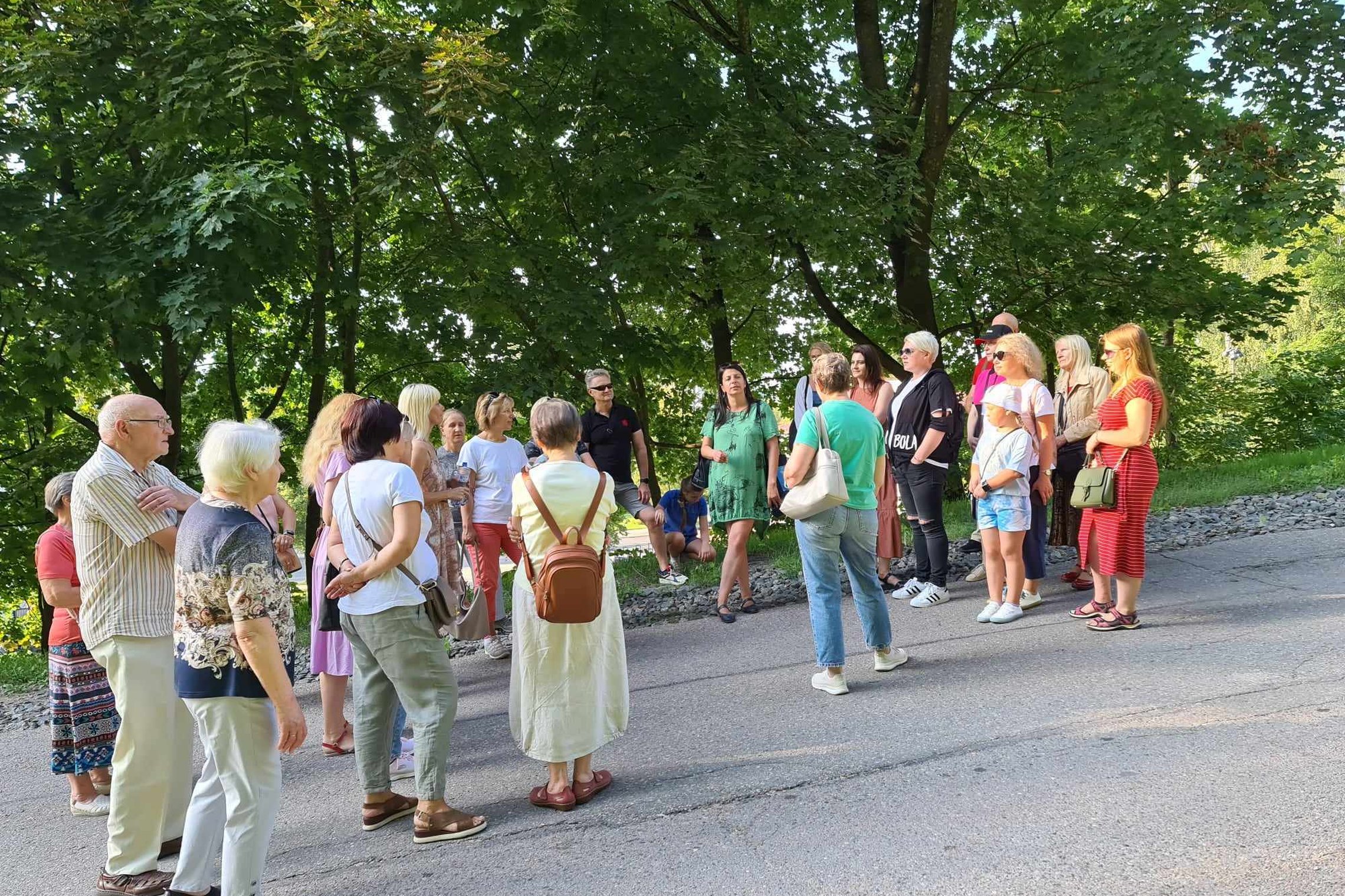 Grupė dalyvių su gide nusiteikę vasariškai prie Trijų kryžių kalno.