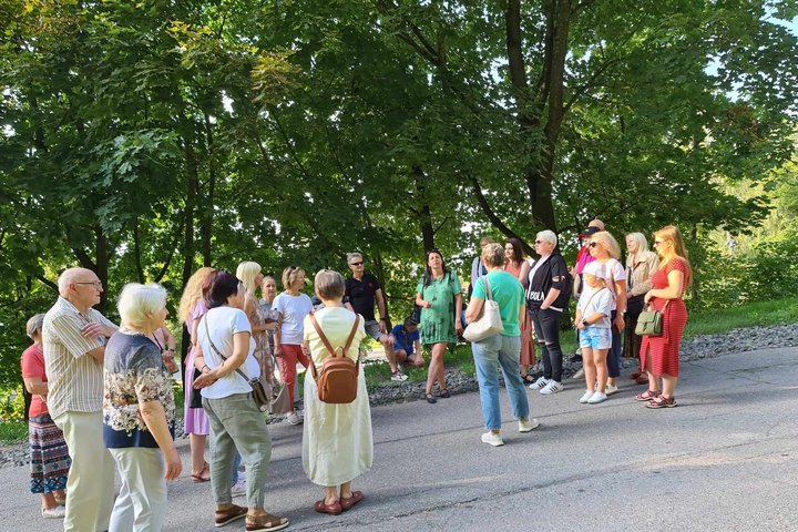 Grupė dalyvių su gide nusiteikę vasariškai prie Trijų kryžių kalno.