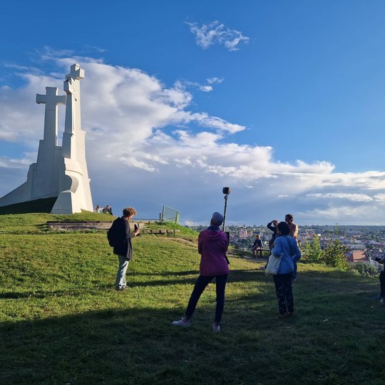 Gidas pasakoja legendas ant Trijų Kryžių kalno aikštelės, iš kairės matosi Trijų Kryžių paminklas.