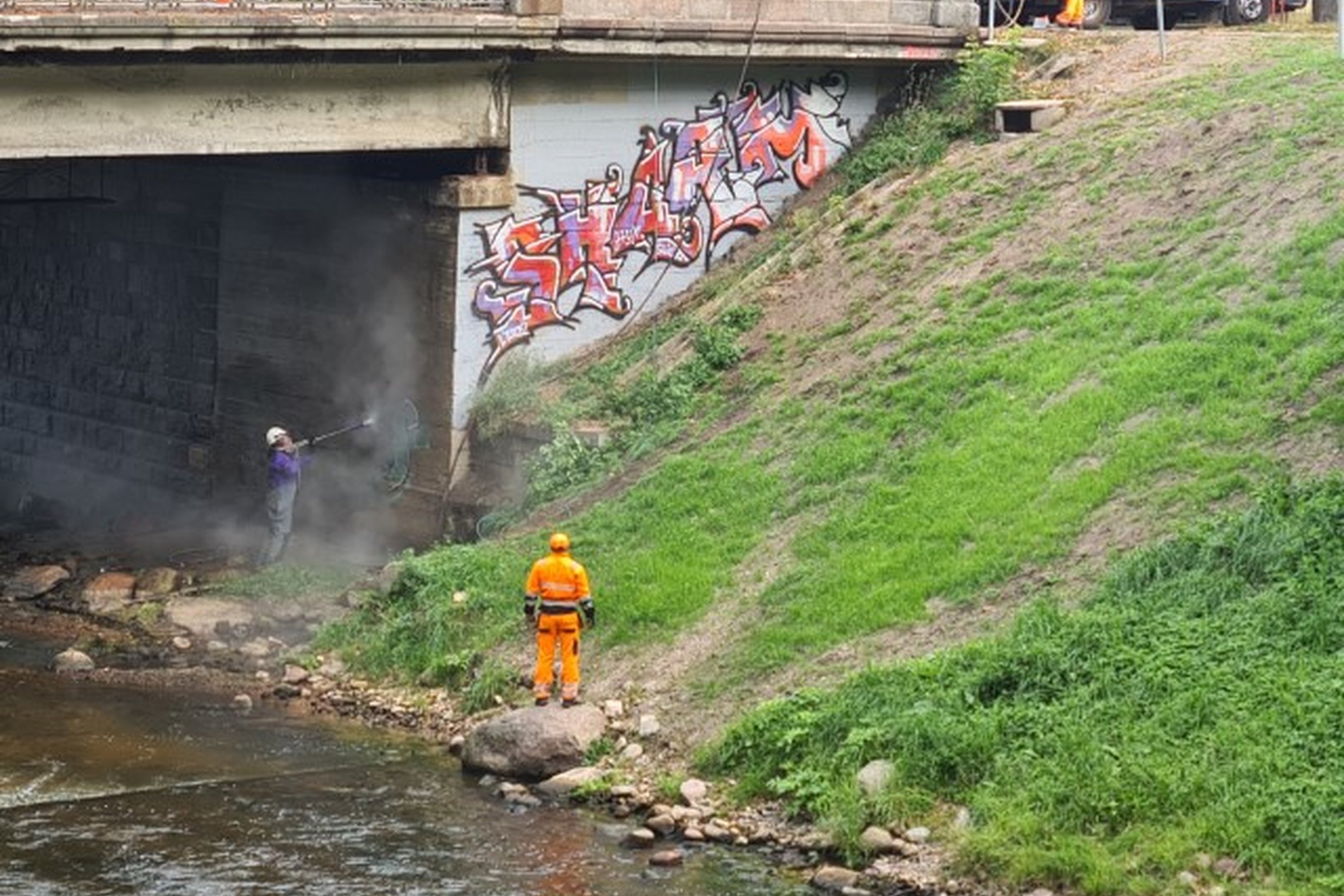 Vilniaus miesto savivaldybės administracijos pasitelkti tiekėjai valo graffiti nuo tilto.