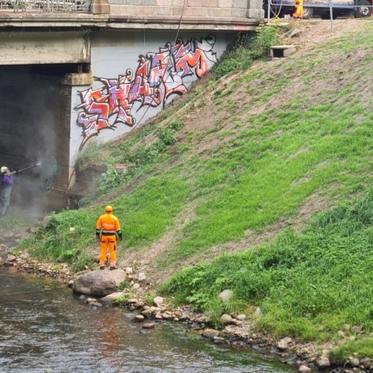 Vilniaus miesto savivaldybės administracijos pasitelkti tiekėjai valo graffiti nuo tilto.