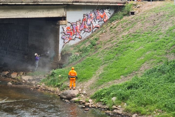 Vilniaus miesto savivaldybės administracijos pasitelkti tiekėjai valo graffiti nuo tilto.