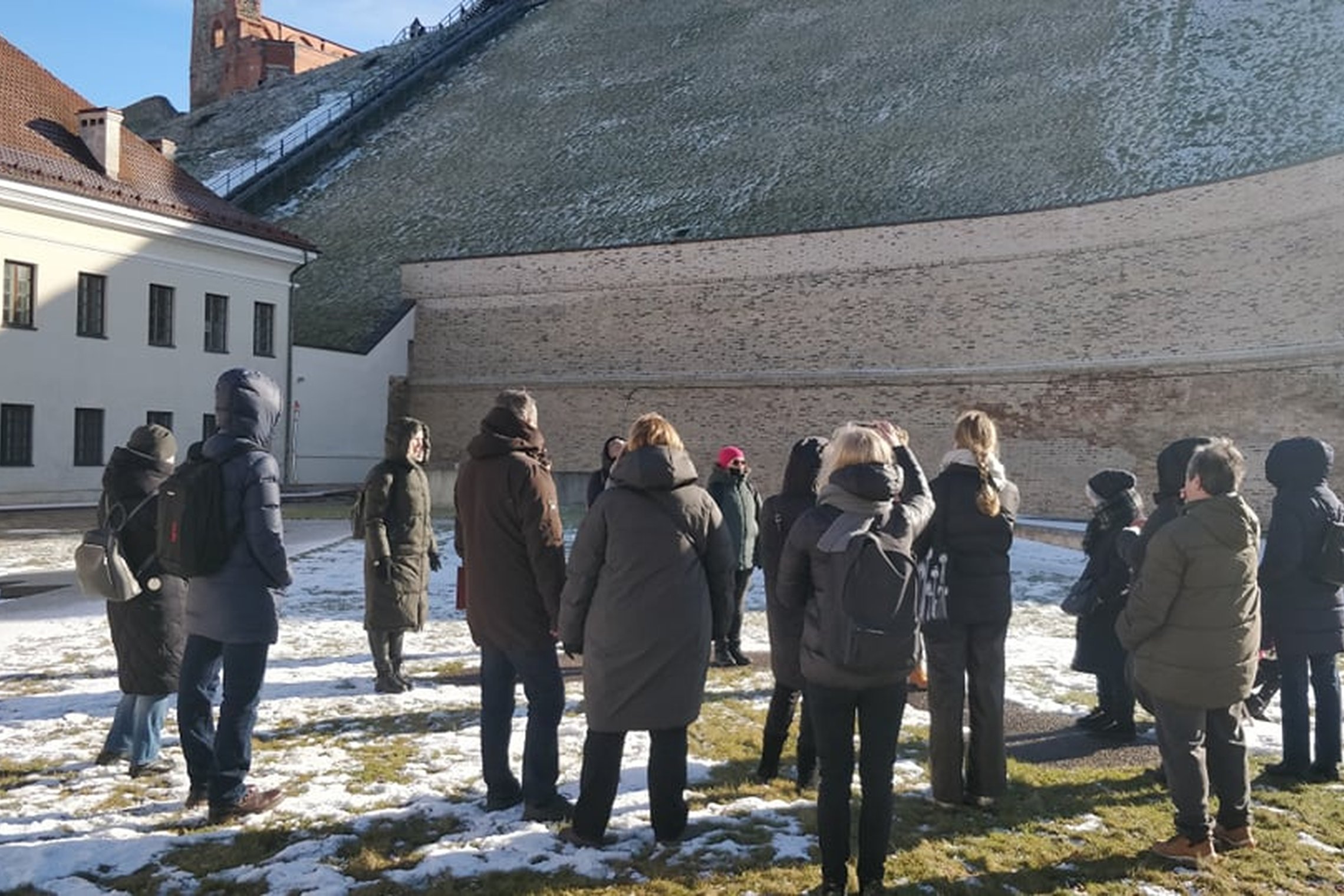 Ekskursijos dalyviai ant Barboros bažnyčios pamatų, šalia didžiosios, atraminės Gedimino kalno sienos.