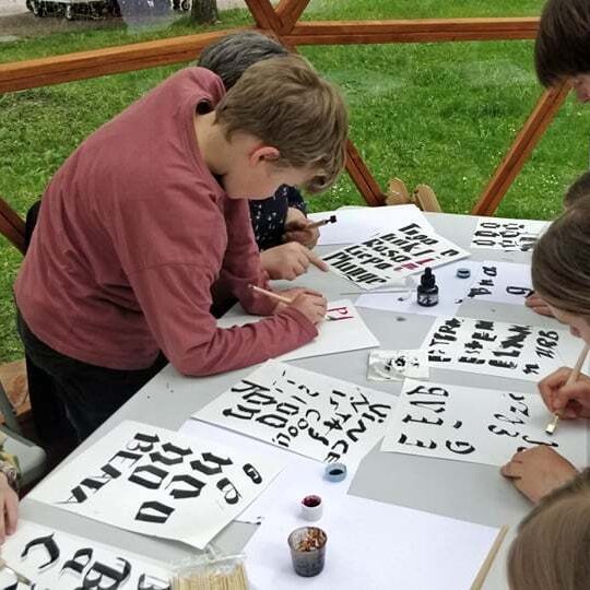 Vilniaus pilių kupole vaikai su tėvais mokosi gotikinių raidžių rašymo.