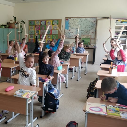 Pirmokai sėdi suoluose iškėlę medinius kalavijus.