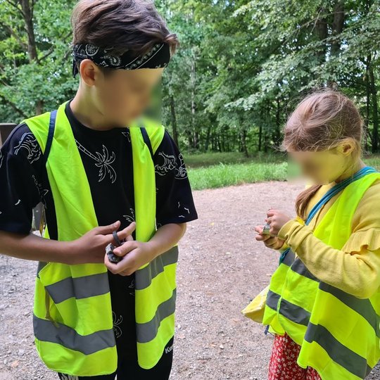 Vaikai smalsiai mokosi naudotis senoviškais ugnies kūrimo įrankiais - skiltuvais.