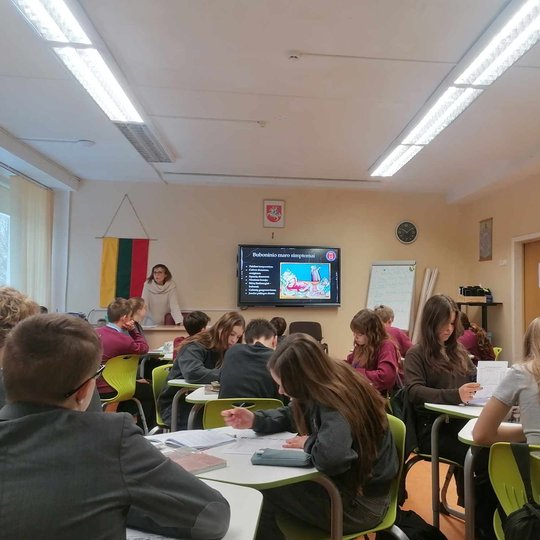 Mokiniai sėdi klasėje, edukatorė veda pamoką apie Buboninį marą.