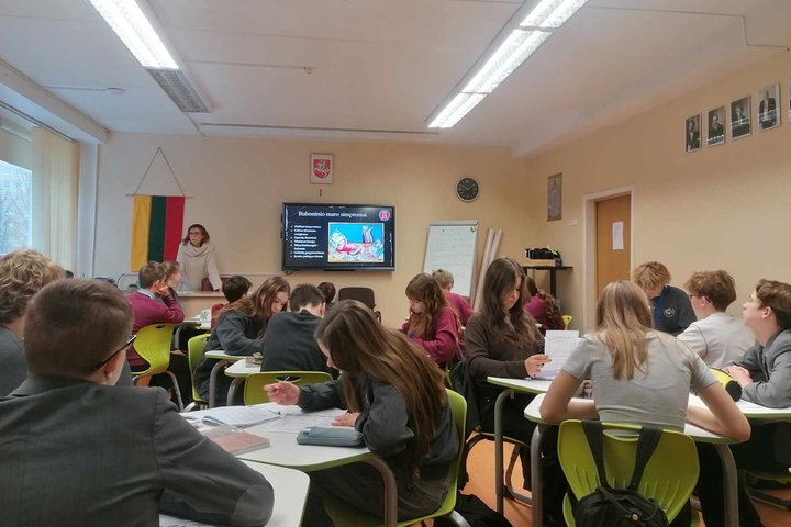 Mokiniai sėdi klasėje, edukatorė veda pamoką apie Buboninį marą.