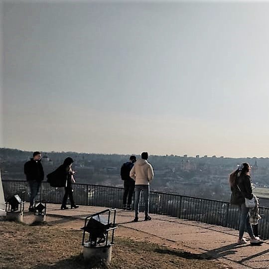 Žmonės mėgaujasi Vilniaus panorama nuo Trijų Kryžių kalno.