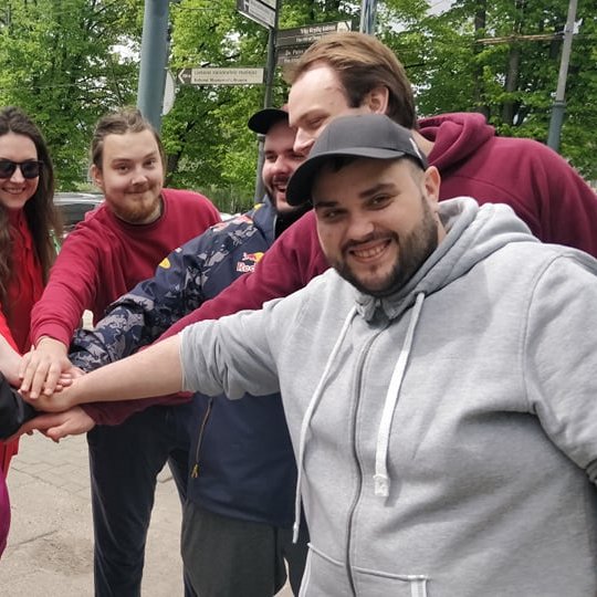 Savanoriai pozuoja vieningai nuotraukai, sudėję rankas į rato centrą.