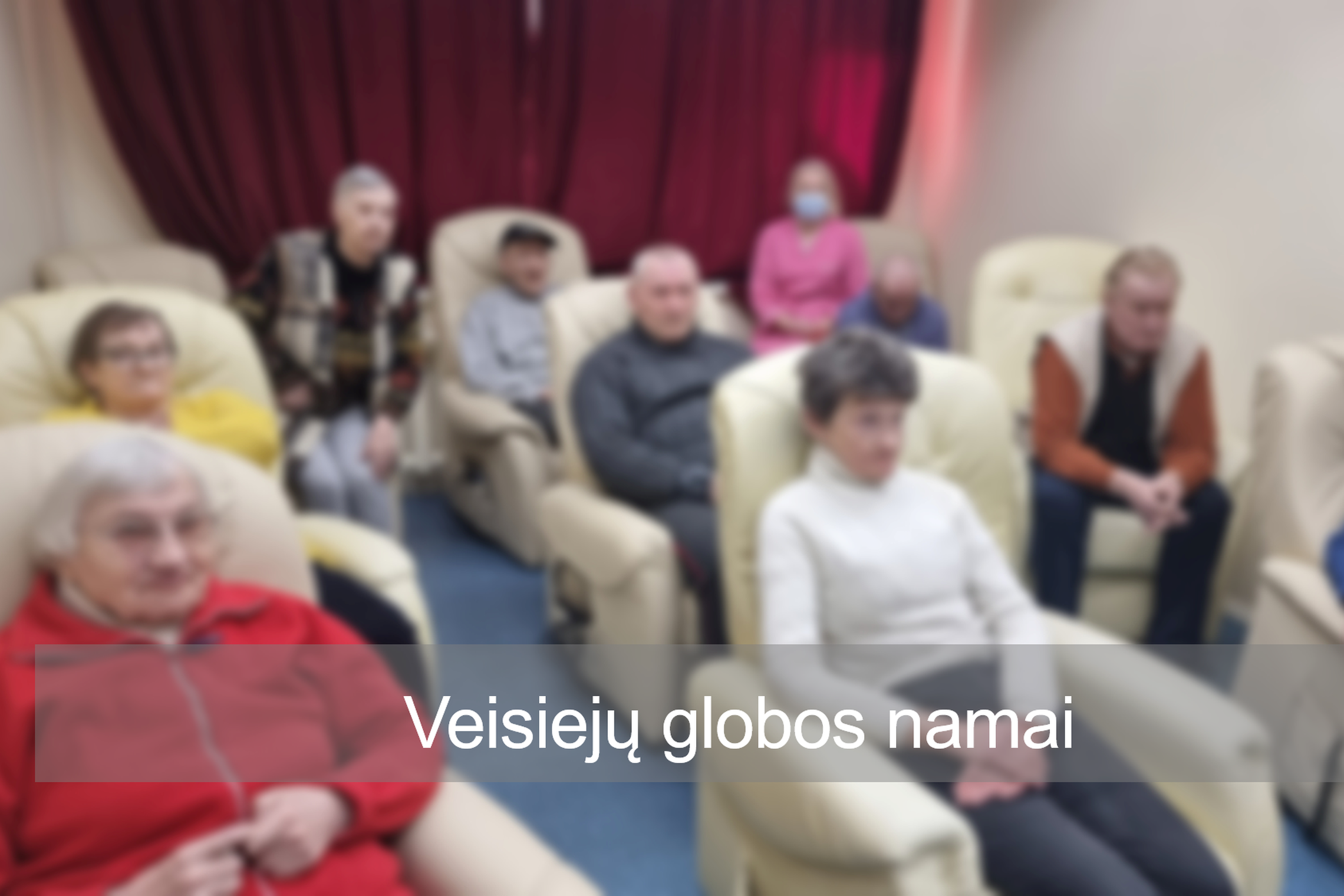 Veisiejų socialinės globos namų gyventojai patogiai klausosi nuotolinės paskaitos. Nuotraukos priekyje įstaigos pavadinimas. 