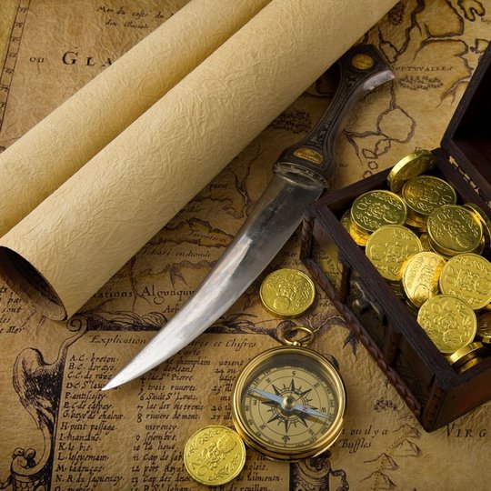 Atvira auksinių monetų skrynia, šalia senoviškas kompasas ir durklas bei senoviškas žemėlapis.