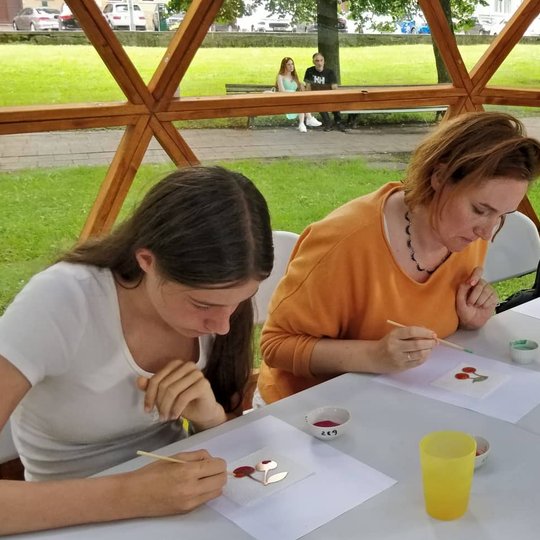 Trys moterys emaliuoja vyšnias ant stalo Vilniaus pilių kupole.