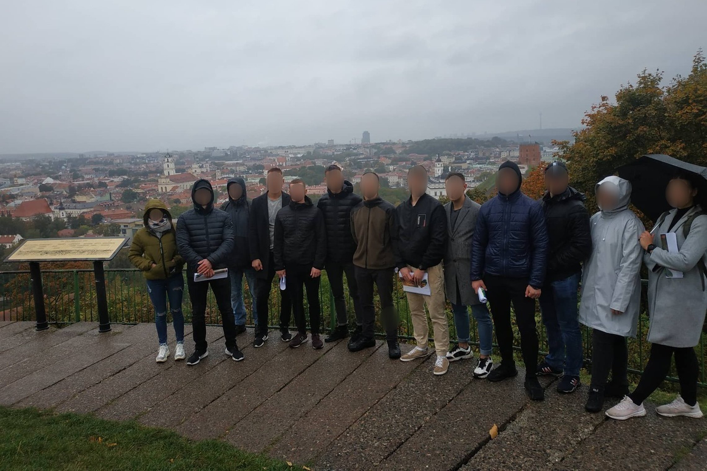 Lietinga vakarą, ant Trijų Kryžių kalvos, 4 kurso karo akademijos kadetai pozuoja nuotraukai. Jiems už nugarų Vilniaus panorama.