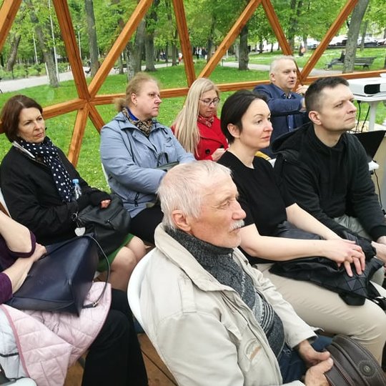 Žmonės įdėmiai klausosi paskaitos. 