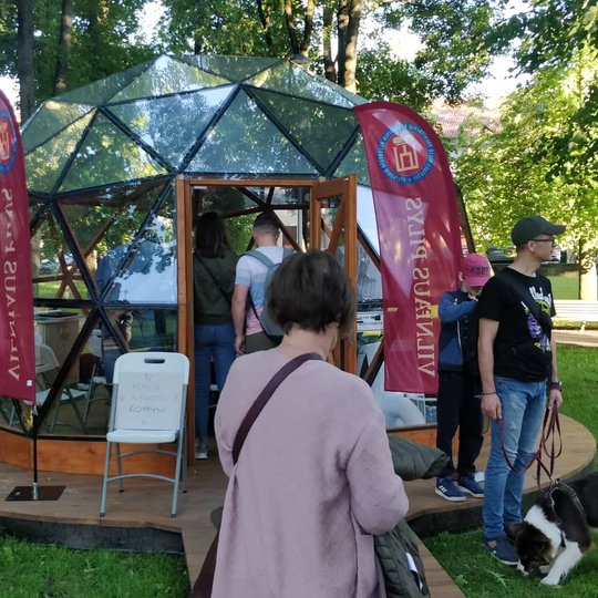 Lankytojai eina pasižiūrėti kas vyksta pilių kupole. Iš kupolo dešinės vyriškis su šuniu.