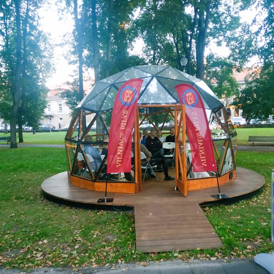 Vilniaus pilių kupolas iš lauko. Kupolo viduje žmonės klausosi archeologės Agnės paskaitos.