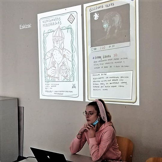 Studentė pristato savo darbo eskizą, kuriame kunigaikštis Gediminas pavaizduotas žaidimo kortoje.
