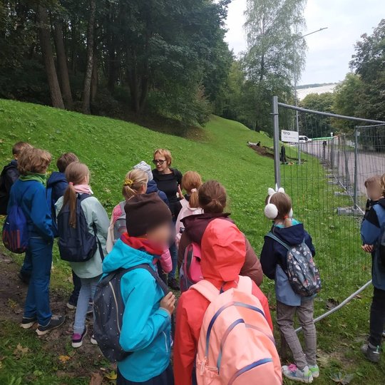 Ketvirtokai klausosi archeologės Dovilės Kreivosios pilies šlaite.