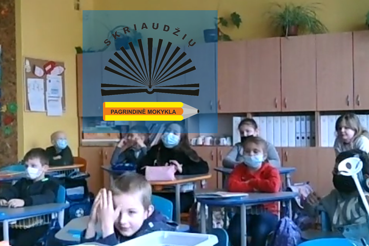 Mokiniai sėdi prie suolų klasėje. Nuotraukos priekyje Skriaudžių pagrindinės mokyklos logotipas.