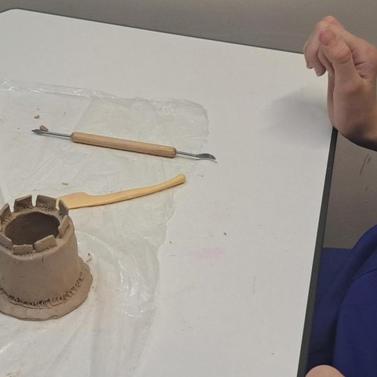 Nuotrauka: ant didelio padėklo išdėlioti vienuolika lipdinių iš molio. Šalia visų darbų esantis didelis Gedimino pilies maketas. Ant kiekvieno lipdinuko užrašytas kūrėjo vardas.