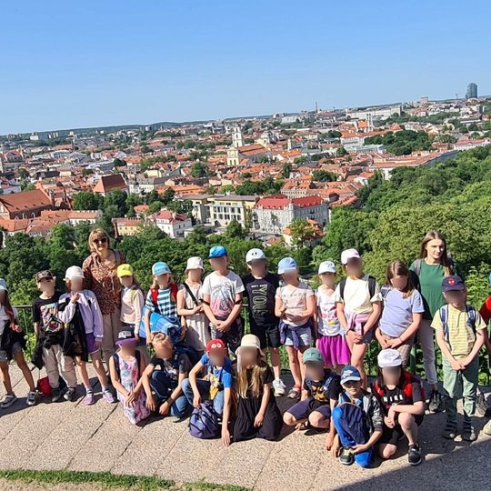 Visa grupė žiniukų ir mokytojos priešais Vilniaus senamiesčio vaizdą, ant Trijų kryžių kalno.