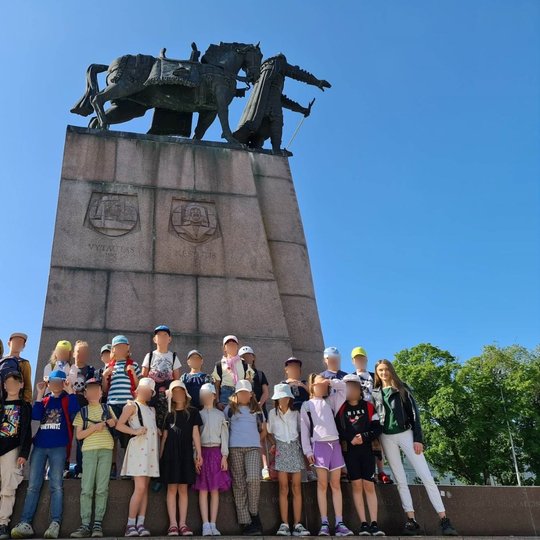 Grupė Vilniaus kunigaikščio Gedimino progimnazijos mokinių pozuoja prie didingo Gedimino paminklo.
