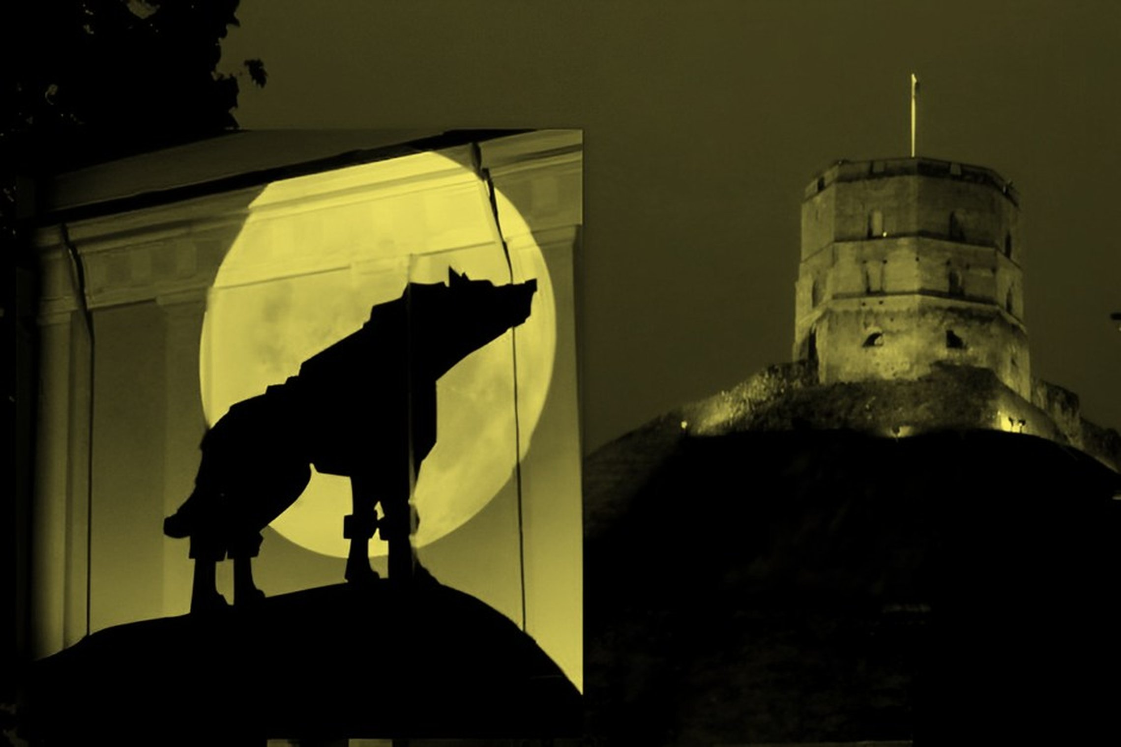 Šviesos instaliacijoje matomas geležinis vilkas pilnaties fone ir Gedimino pilis.